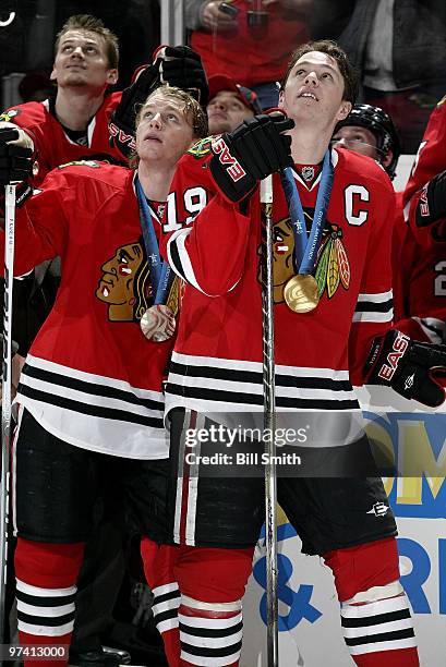 Winter Olympic silver medalist Patrick Kane and gold medalist Jonathan Toews of the Chicago Blackhawks watch the video board before a game against...