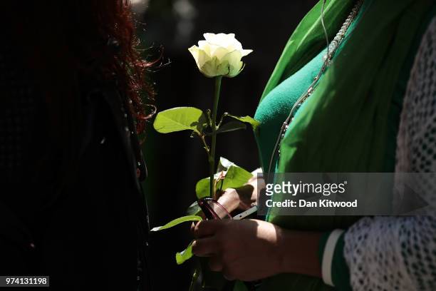 Woman holds a white rose in tribute as she takes part in the walk to the Wall of Truth to mark the one year anniversary of the Grenfell Tower fire on...