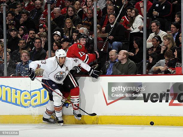 Jason Strudwick of the Edmonton Oilers pushes Jonathan Toews of the Chicago Blackhawks into the glass on March 03, 2010 at the United Center in...