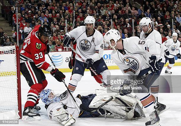 Dustin Byfuglien of the Chicago Blackhawks, Jason Strudwick, and Johan Motin of the Edmonton Oilers work to get the puck, which lands on goalie Devan...