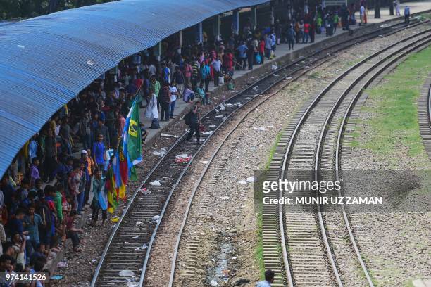 Bangladeshi vendor carrying national flags of countries competing in the forthcoming 2018 Fifa World Cup 2018 waits for customers at a train station...