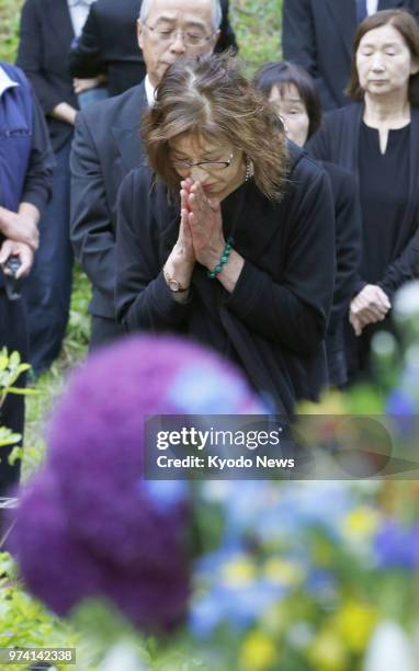 Woman offers prayers in Kurihara, Miyagi Prefecture, on June 14 nearby the former site of Komanoyu hot-spring inn, which was engulfed by a landslide...