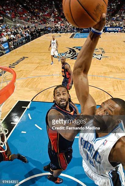Dwight Howard of the Orlando Magic slam dunks against Ronny Turiaf of the Golden State Warriors during the game on March 3, 2010 at Amway Arena in...