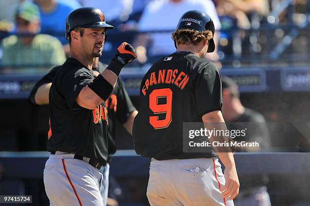 Aaron Rowand of the San Francisco Giants congratulates Kevin Frandsen after scoring against the Seattle Mariners during a spring training game at...