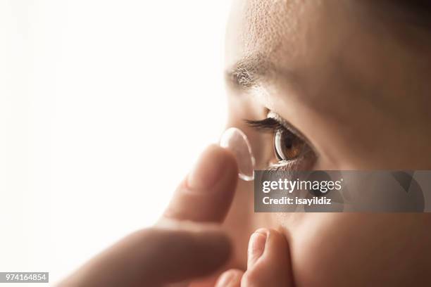 mujer utilizando una lente de contacto - lente de contacto fotografías e imágenes de stock