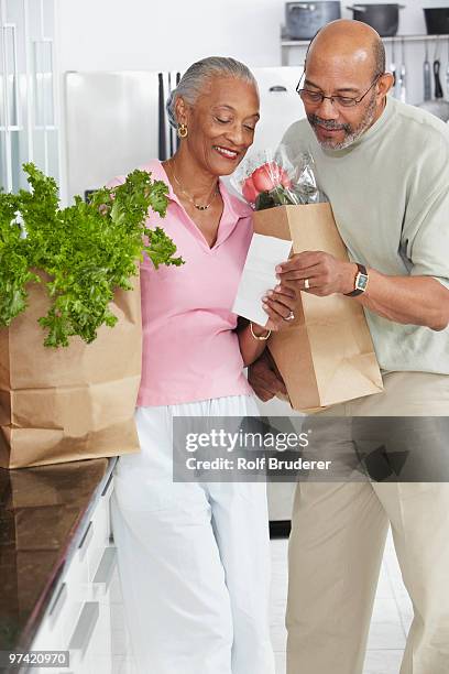 african couple grocery shopping - cutting costs stock pictures, royalty-free photos & images