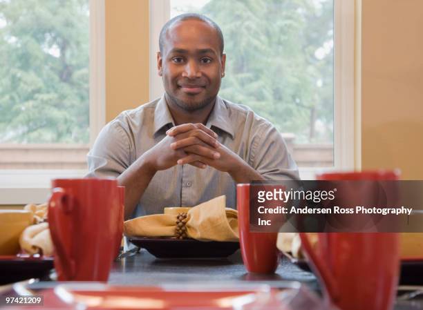 african man sitting at set table - los angeles no kid hungry dinner stock pictures, royalty-free photos & images
