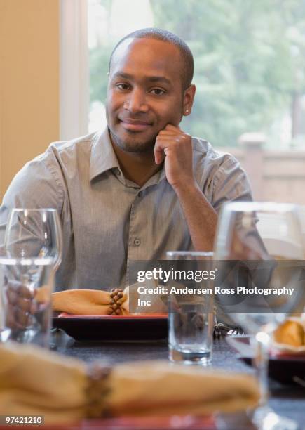 african man sitting at set table - los angeles no kid hungry dinner stock pictures, royalty-free photos & images