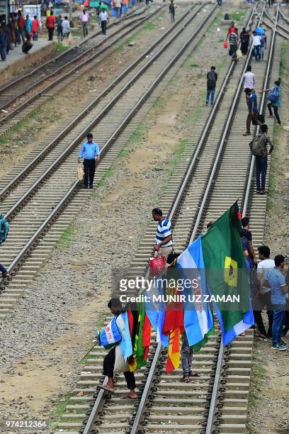 Bangladeshi vendor carrying national flags of countries competing in the forthcoming Fifa 2018 World Cup waits for customers at a train station as...