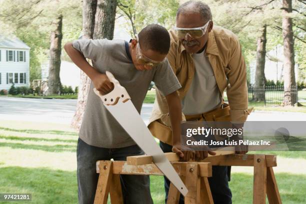 african grandfather watching grandson saw wood - cortando atividade - fotografias e filmes do acervo