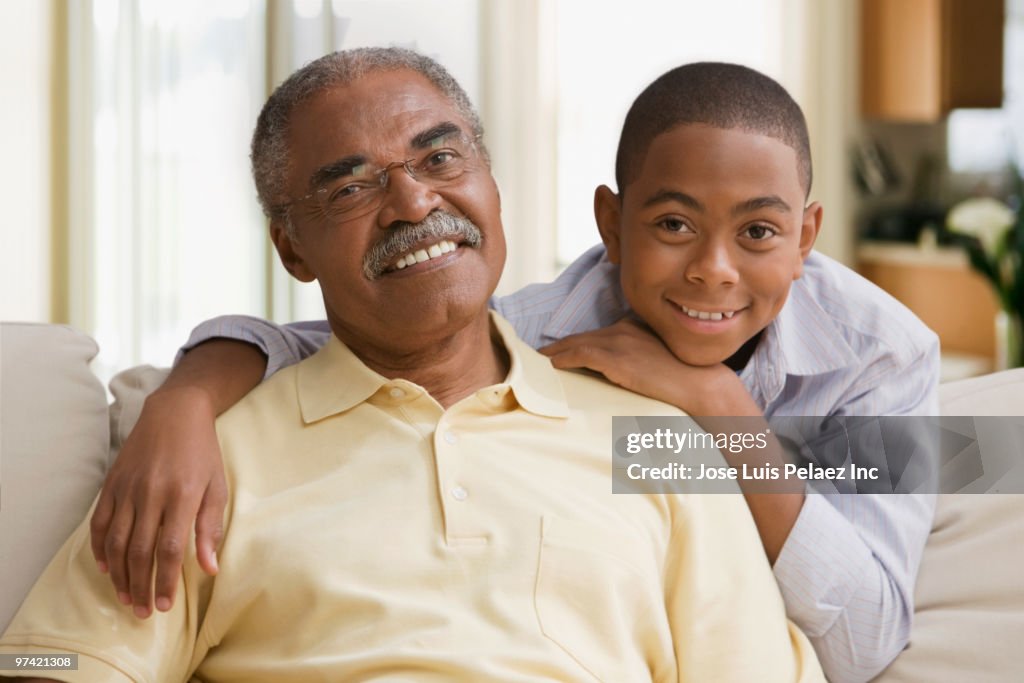 African grandfather and grandson sitting on sofa