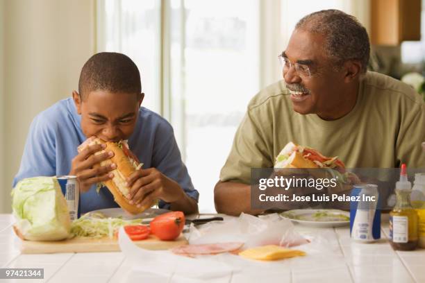 african grandfather and grandson eating lunch - sandwich generation stock pictures, royalty-free photos & images