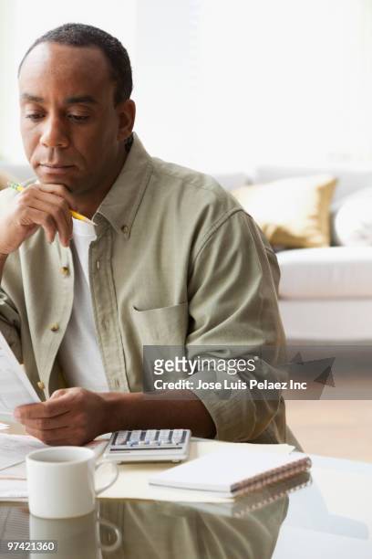 african man paying bills - coffee table reading mug stock pictures, royalty-free photos & images