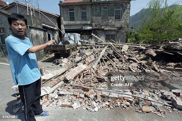 Man points at a quake-damaged house in the town of Shanlin, in the southern Taiwan county of Kaohsiung on March 4, 2010 after the powerful quake...