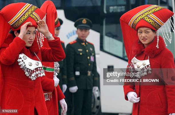 Chinese paramilitary policemen watch as a hostess dressed in ethnic-minority costume adjusts her headgear on Tiananmen Square in Beijing on March 4,...