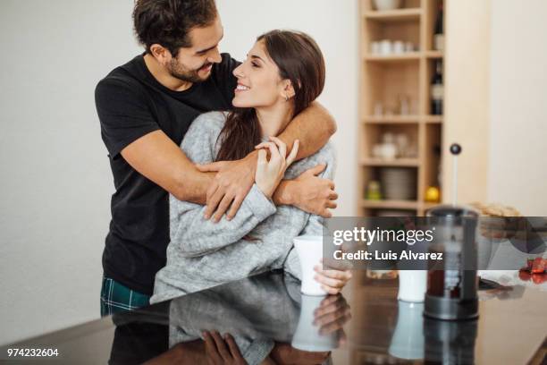 romantic couple embracing at kitchen island - kitchen coffee home stock-fotos und bilder