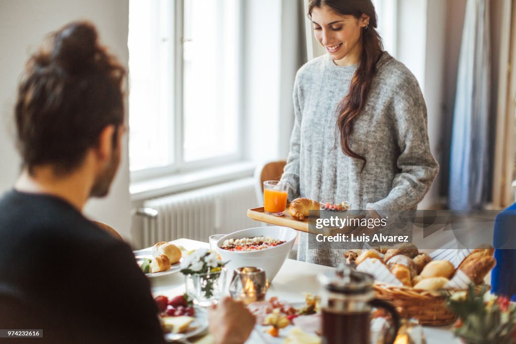 Woman serving breakfast to boyfriend at table