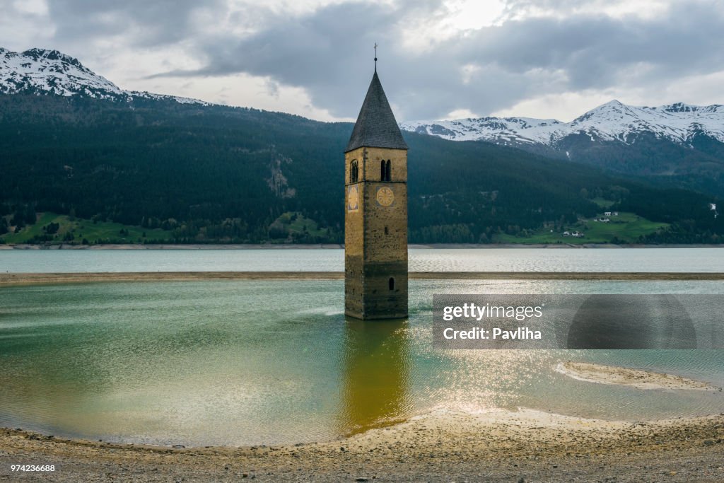 Kerk onder water, verdronken dorp, landschap van bergen en toppen op achtergrond. Reschensee Lake Reschen Lago di Resia. Italië, Europa, Südtirol, Zuid-Tirol, Opper-Tirol, Skiparadies