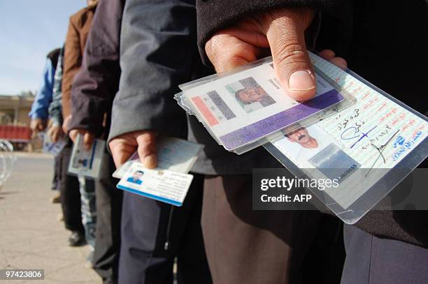 Iraqi security forces carry their IDs as they queue at the entrance of a polling station in Ramadi, west of the Iraqi capital Baghdad, to vote in the...