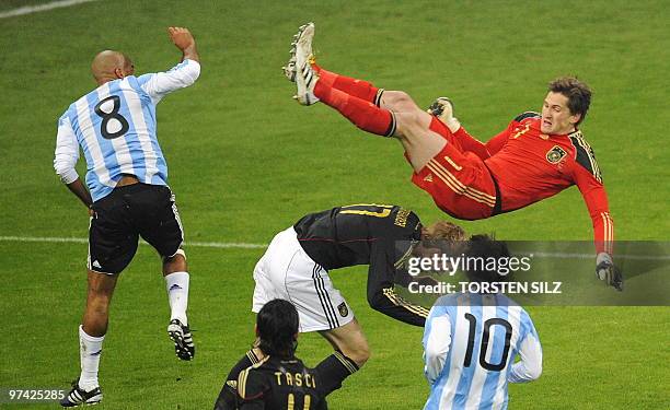 Germany's goalkeeper Rene Adler jumps over teammate defender Per Mertesacker as he vies for the ball with Argentina's midfielder Juan Sebastián Verón...