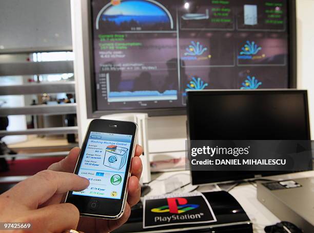 An exhibitor uses a smartphone to control a washing machine by HydraGyzer energy management system at the world's biggest high-tech fair, the CeBIT...