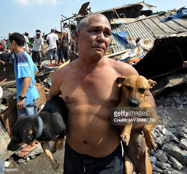 Resident carries his pet dogs as his house is demolished by workers of the Department of Public Work and Highways in Navotas City suburban Manila on...