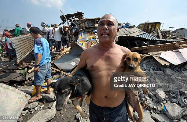 Resident carries his pet dogs as his house is demolished by workers of the Department of Public Work and Highways in Navotas City suburban Manila on...