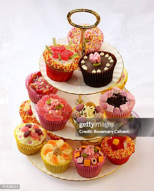 brightly decorated cupcakes on tiered cake stand - cake stand stockfoto's en -beelden