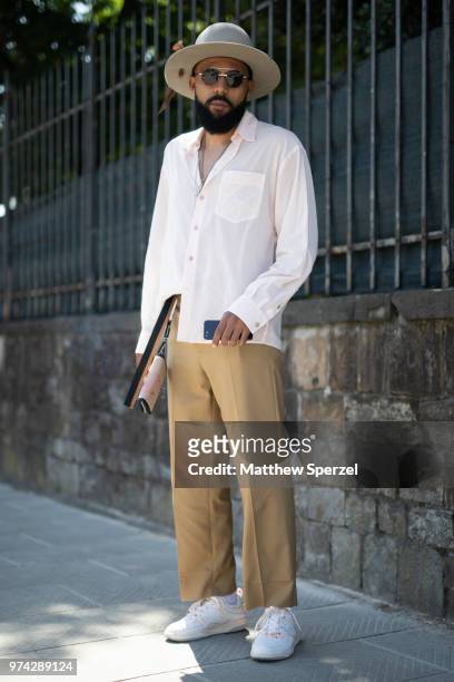 Guest is seen on the street attending Pitti Uomo 94 wearing a white linen shirt, khaki pants, white sneakers and grey hat on June 12, 2018 in...