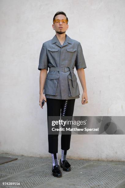 Guest is seen on the street attending Pitti Uomo 94 wearing a grey coat with black pants and orange tint glasses on June 12, 2018 in Florence, Italy.