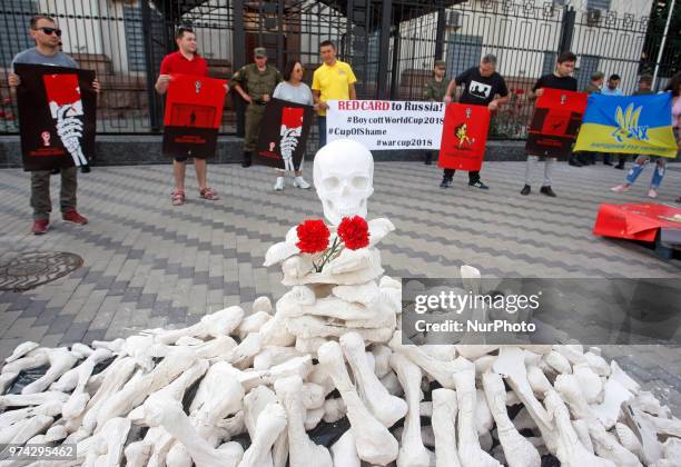 Activists hold placards by artist Andriy Yermolenko during a rally with an appeal to boycott the Russia World Cup 2018 football tournament, and...