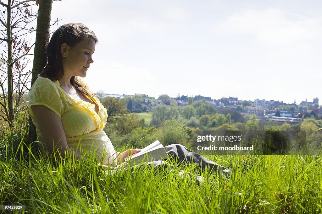 Pregnant woman sitting on grass