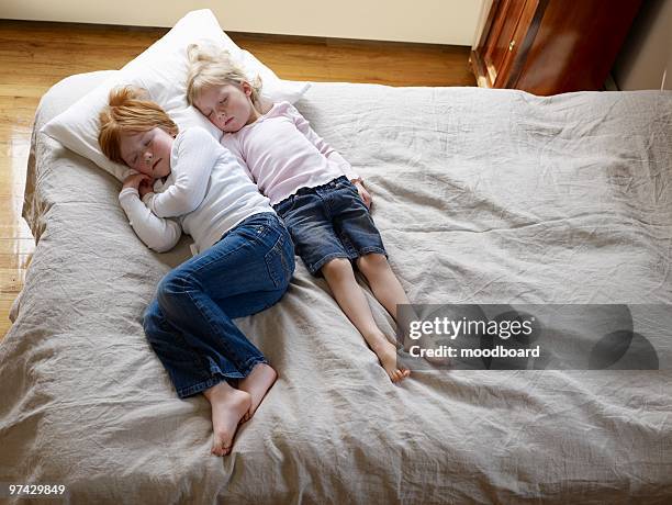 two sisters lie sleeping on a bed, elevated view - eenpersoonsbed stockfoto's en -beelden
