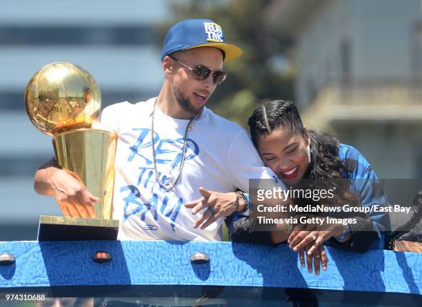 Stephen Curry holds the Larry O'Brien NBA Championship Trophy as he and his wife Ayesha Curry ride atop a bus during the Golden State Warriors...