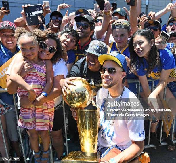 Stephen Curry holds the Larry O'Brien NBA Championship Trophy as he and his daughter Riley are photographed with fans during the Golden State...