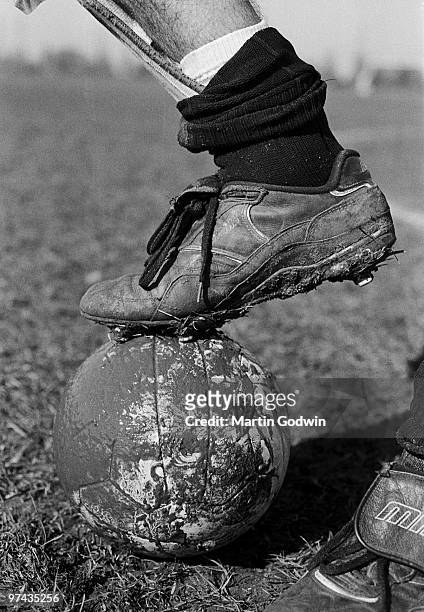 Close up of muddy football boot on muddy football. Sunday football at Hackney Marshes, London E9, 5th March 1995.