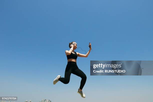 young woman jumping and listening music - in de lucht zwevend stockfoto's en -beelden