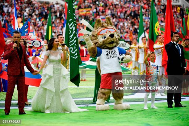 English singer Robbie Williams performs with Russian soprano Aida Garifullina as Brazilian football ledgend Ronaldo waves during the opening ceremony...