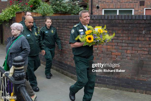 Ambulance staff carry flowers while attending the memorial service on the first anniversary of the Grenfell tower block disaster, on 14th June 2018,...