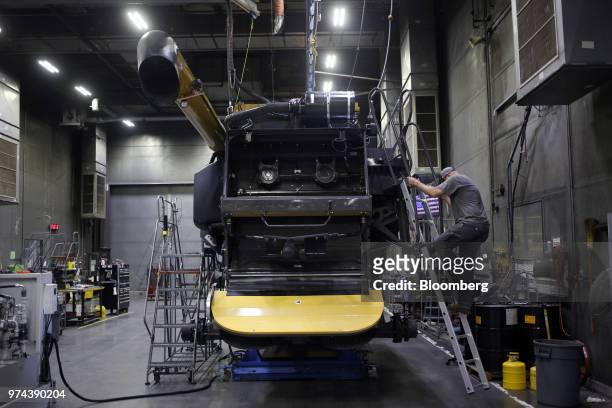 Worker climbs a ladder while assembling a combine harvester at the CLAAS of America Inc. Production facility in Omaha, Nebraska, U.S., on Wednesday,...