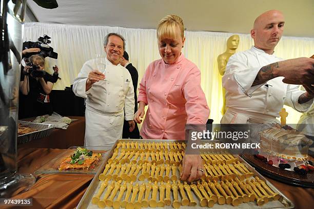 Executive pastry chef Sherry Yard arranges gold-covered chocolate Oscar statuettes as Governors Ball master chef Wolfgang Puck looks on, at a preview...