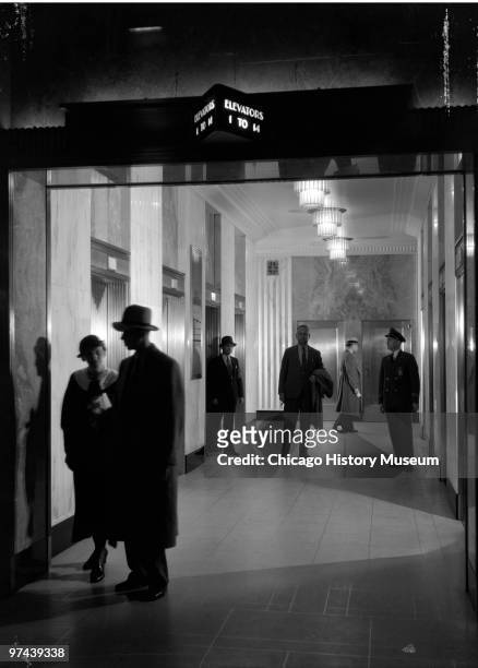Interior views of an elevator lobby in the Field Building at 135 South LaSalle Street, Chicago, IL, 1933. The view shows the area with people posed...
