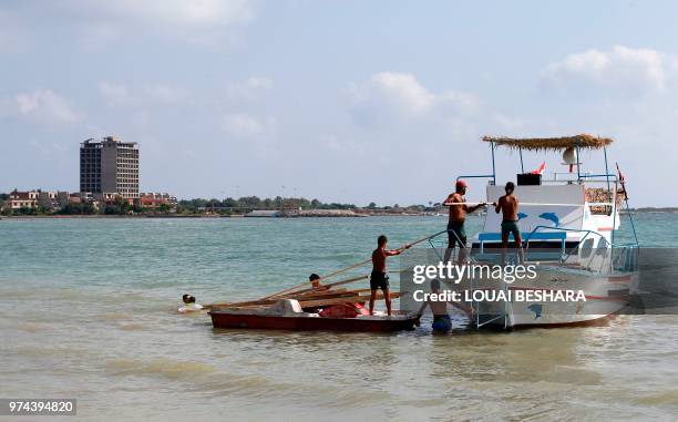 Syrian men transship wooden batten in Latakia on June 14, 2018.