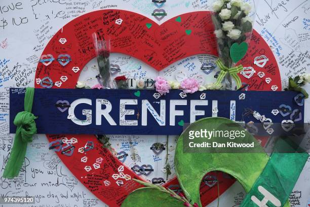 Messages and flowers are left on a sign which has been decorated with a green scarf on a memorial wall near Grenfell Tower on the one year...