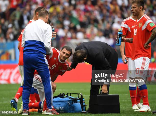 Russia's midfielder Alan Dzagoev is treated by medical staff after being injured during the Russia 2018 World Cup Group A football match between...