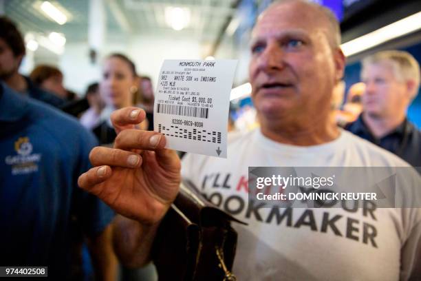 Professional odds-maker Stu Feiner holds up a betting slip for $5000 USD on June 14, 2018 after placing a bet at the Monmouth Park Sports Book on the...