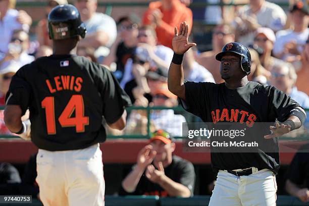 Juan Uribe of the San Francisco Giants celebrates with teammate Fred Lewis after scoring two runs off a double by Eli Whiteside against the Milwaukee...