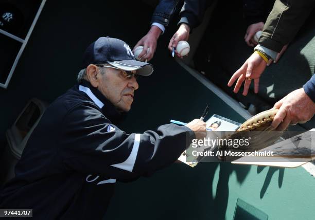 Coach Yogi Berra of the New York Yankees signs an autograph before play against the Philadelphia Phillies March 4, 2010 at the Bright House Field in...