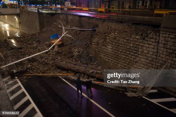 Taxi plummeted towards the ground as the heavy rainstorm cause the wall collapse at Beijing street on June 14, 2018 in Harbin, China.Two people were...