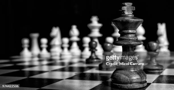 king chess piece on chessboard - chess fotografías e imágenes de stock
